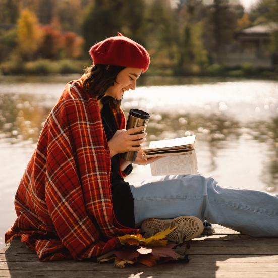 Kvinde, der læser en bog ved en sø.