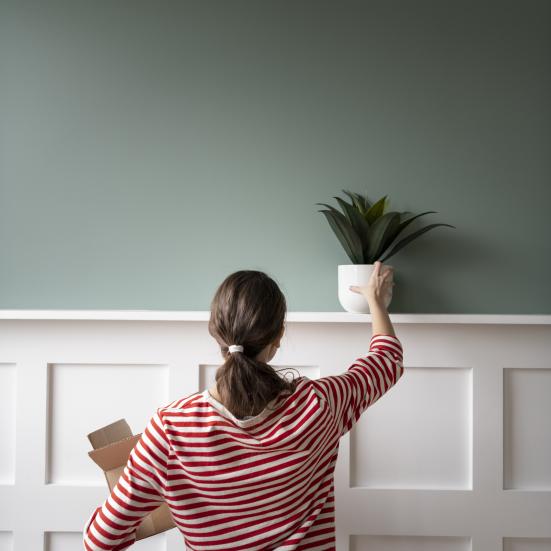 Kvinde, der stiller en plante på et vægpanel.